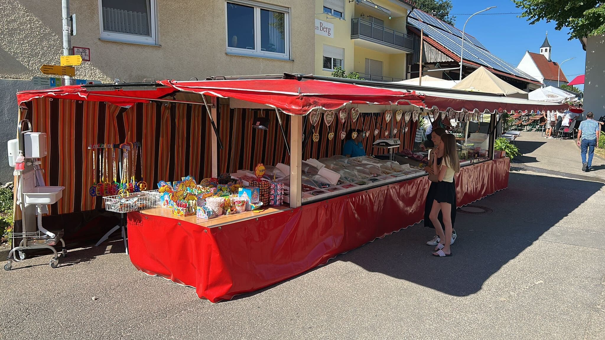 Roter Süßwarenstand mit Markise und Lebkuchenherzen an einer Straße